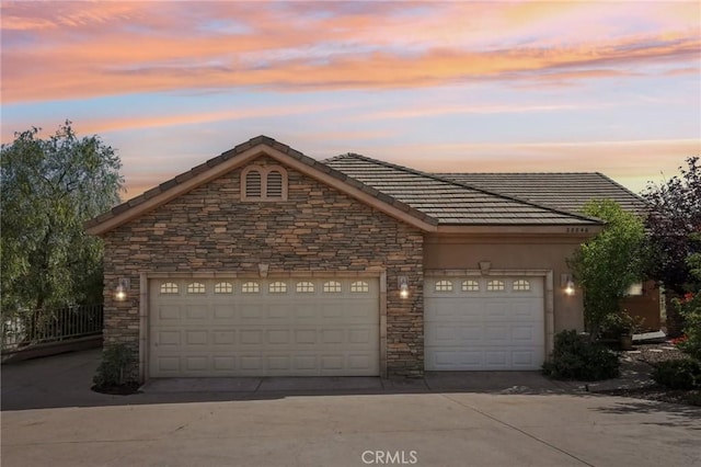28846 Yosemite Pl, Canyon Lake, CA 92587 - view of front of home with stone siding, concrete driveway, an attached garage, and a tile roof