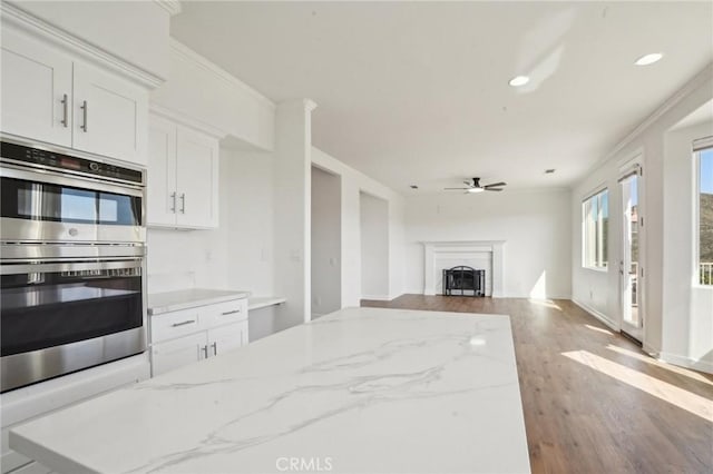 28846 Yosemite Pl, Canyon Lake, CA 92587 - kitchen with double oven, wood finished floors, white cabinets, a fireplace, and ceiling fan