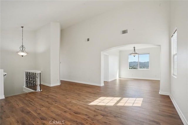 28846 Yosemite Pl, Canyon Lake, CA 92587 - unfurnished living room featuring a towering ceiling, arched walkways, and wood finished floors