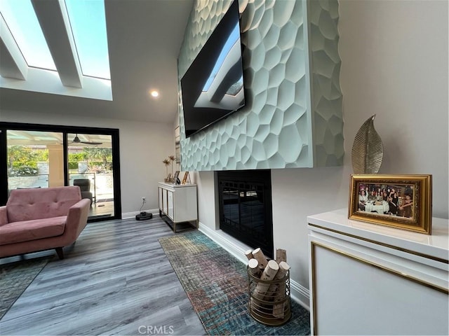 living area with recessed lighting, baseboards, a glass covered fireplace, and wood finished floors