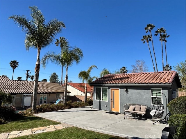 rear view of house with a tile roof, fence, an outdoor hangout area, a patio, and stucco siding