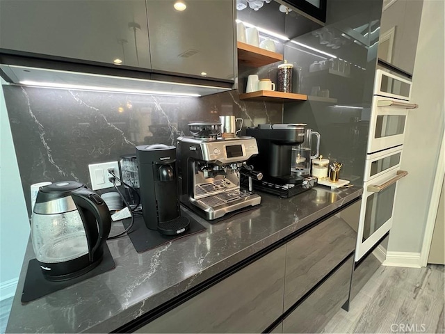 interior space featuring dark stone countertops, open shelves, and light wood-type flooring