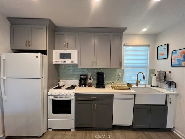 kitchen featuring gray cabinetry, a sink, and white appliances