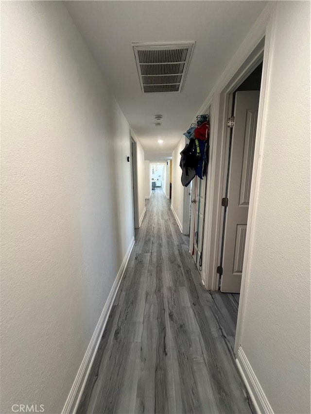 hall with baseboards, wood finished floors, and visible vents