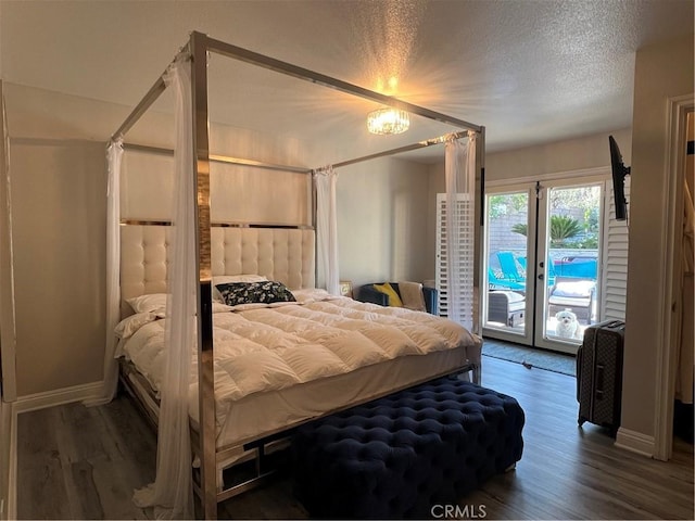 bedroom with baseboards, a textured ceiling, wood finished floors, and access to exterior