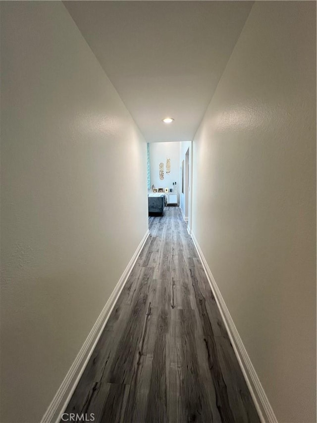 hallway featuring baseboards and wood finished floors