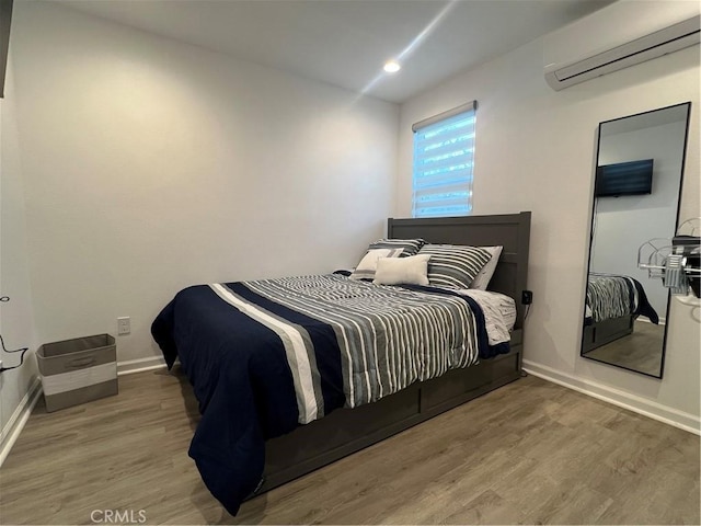 bedroom featuring recessed lighting, baseboards, a wall mounted AC, and wood finished floors