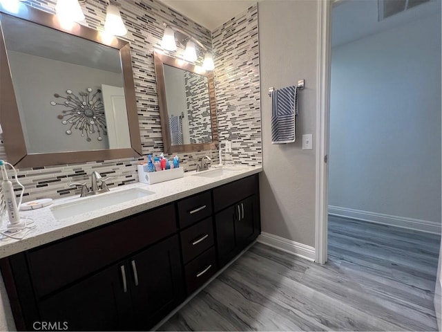 full bathroom with visible vents, a sink, wood finished floors, and tasteful backsplash