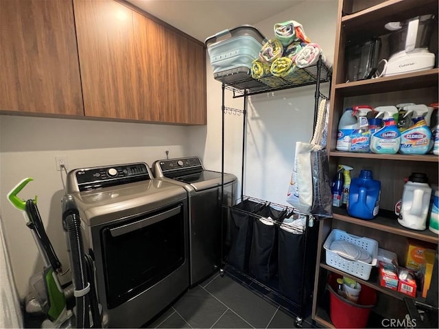 clothes washing area featuring dark tile patterned flooring, cabinet space, and washing machine and clothes dryer