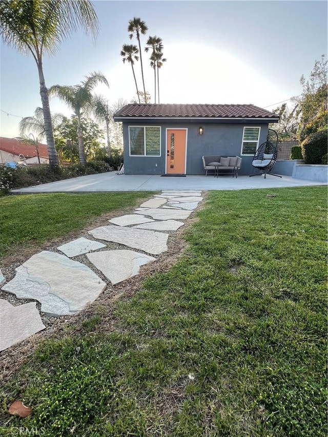 rear view of house featuring outdoor lounge area, stucco siding, a patio area, a yard, and a tile roof