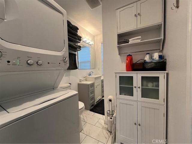 washroom featuring laundry area, visible vents, a sink, marble finish floor, and stacked washer and clothes dryer