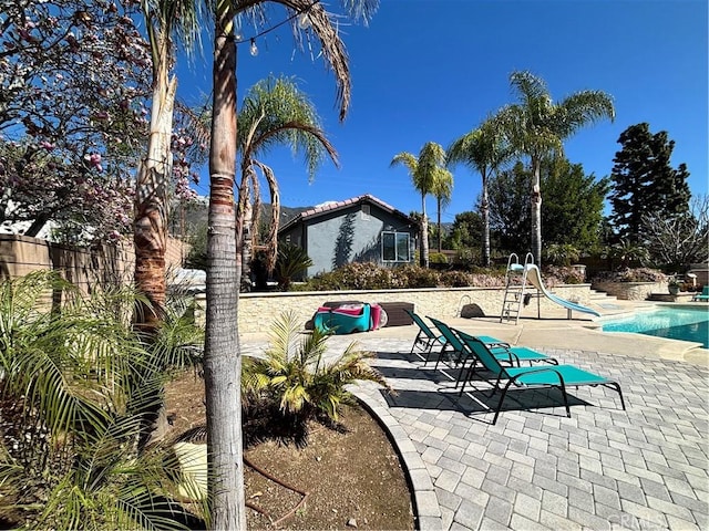 outdoor pool with a water slide and a patio