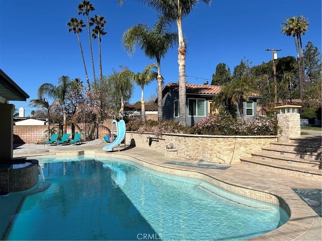 outdoor pool featuring fence, a water slide, and a patio area