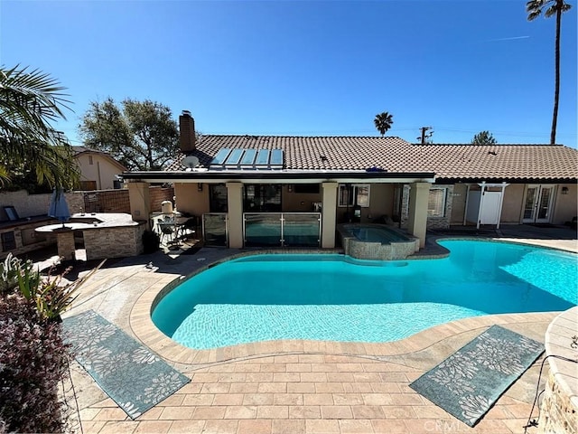 view of swimming pool with area for grilling, a pool with connected hot tub, outdoor dry bar, a patio area, and fence