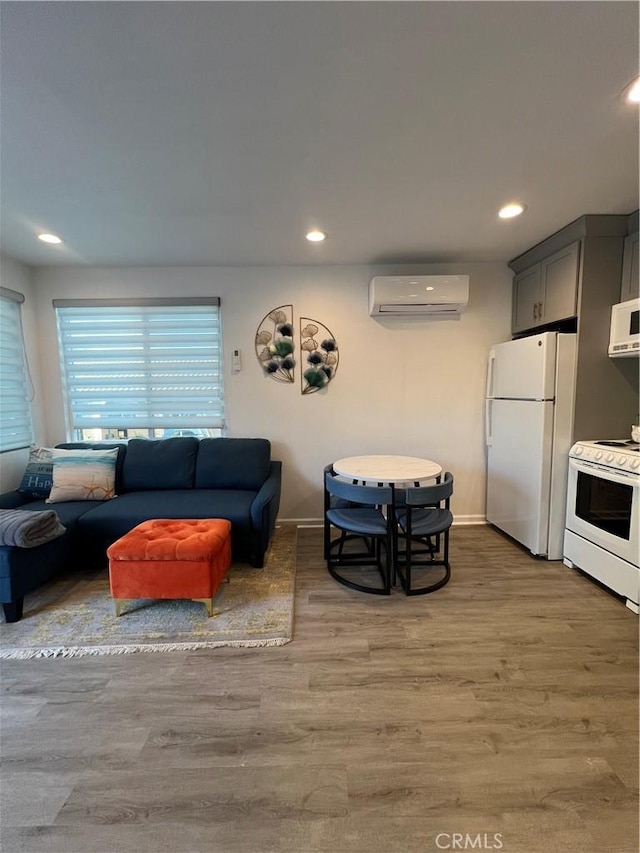living room featuring an AC wall unit, recessed lighting, and light wood-style floors