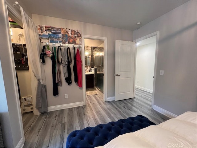 bedroom with baseboards, ensuite bathroom, and wood finished floors
