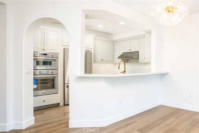 5935 Playa Vista Dr Unit 307, Playa Vista, CA 90094 - kitchen with appliances with stainless steel finishes, light countertops, baseboards, light wood-type flooring, and under cabinet range hood