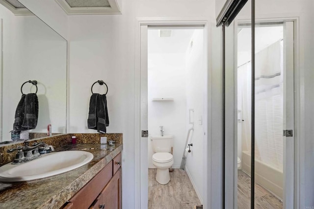 bathroom featuring wood finished floors, toilet, vanity, and baseboards