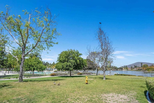 view of home's community with a lawn, fence, and a water and mountain view