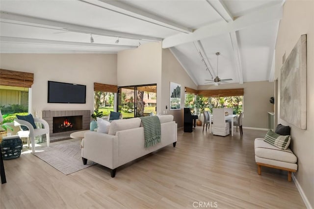 74 Tennis Club Dr, Rancho Mirage, CA 92270 - living area featuring a ceiling fan, a fireplace, baseboards, beamed ceiling, and light wood-style floors
