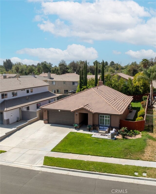 view of front of home featuring a tiled roof, a garage, fence, a front lawn, and concrete driveway