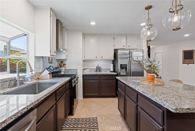 kitchen featuring dark brown cabinetry, a sink, light stone counters, white cabinets, and stainless steel appliances