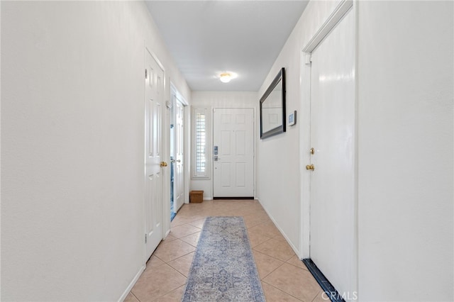 hall with baseboards and light tile patterned flooring