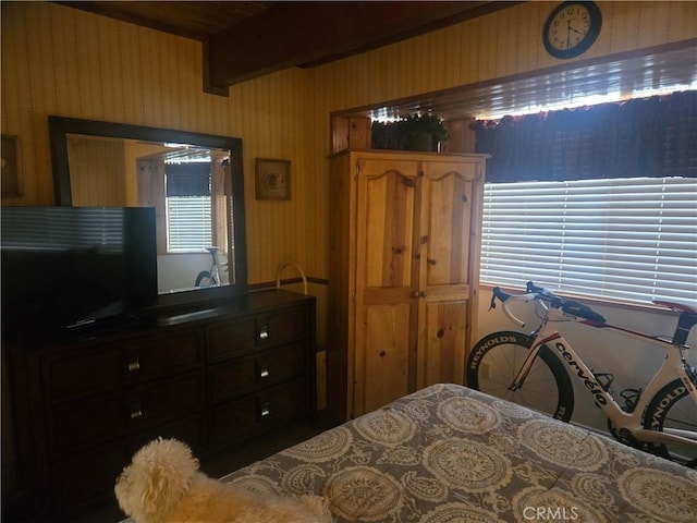 bedroom with beam ceiling and wallpapered walls