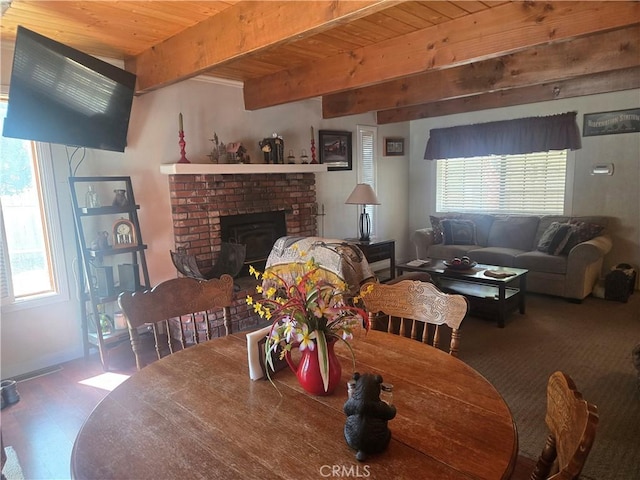 dining area featuring wood ceiling, plenty of natural light, beamed ceiling, and a brick fireplace
