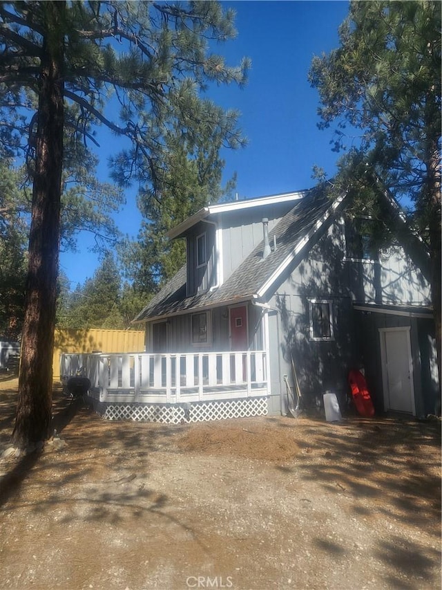view of side of home featuring a porch and a shingled roof