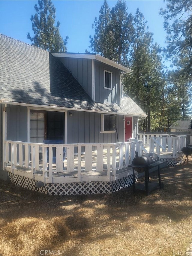 back of house featuring a deck, a shingled roof, and board and batten siding