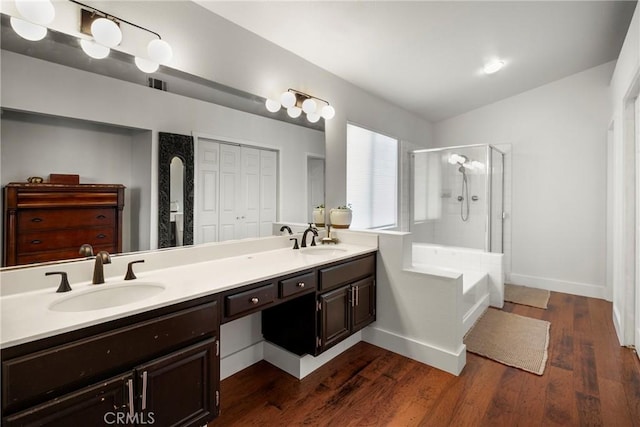 full bath with double vanity, a sink, wood finished floors, and a shower with door