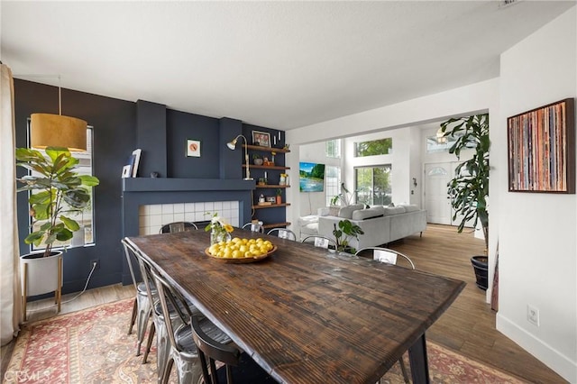 dining space with baseboards, wood finished floors, and a tile fireplace