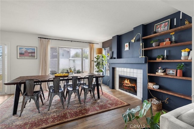 dining area with wood finished floors, a wealth of natural light, and a tile fireplace
