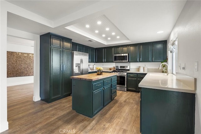 kitchen with recessed lighting, a sink, a center island, appliances with stainless steel finishes, and butcher block counters