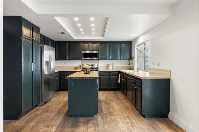 kitchen with recessed lighting, light wood finished floors, a center island, appliances with stainless steel finishes, and butcher block counters