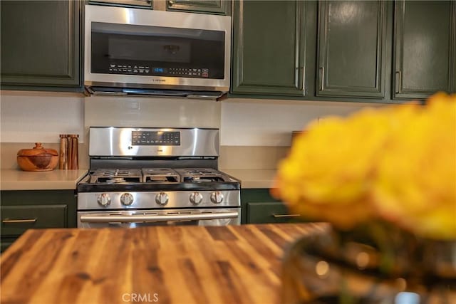 kitchen with green cabinets, wood counters, and appliances with stainless steel finishes