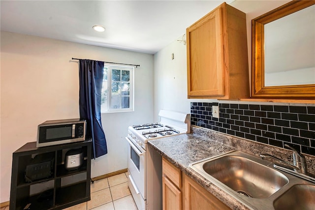 kitchen with stainless steel microwave, a sink, white range with gas cooktop, light tile patterned flooring, and backsplash