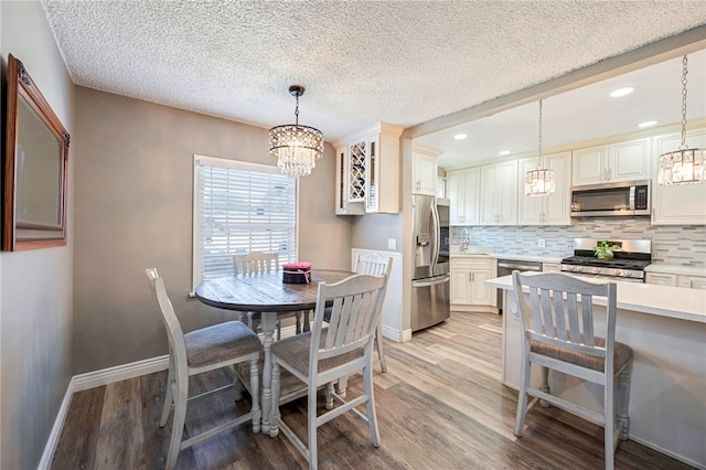 dining area featuring a chandelier, light wood-type flooring, recessed lighting, and baseboards