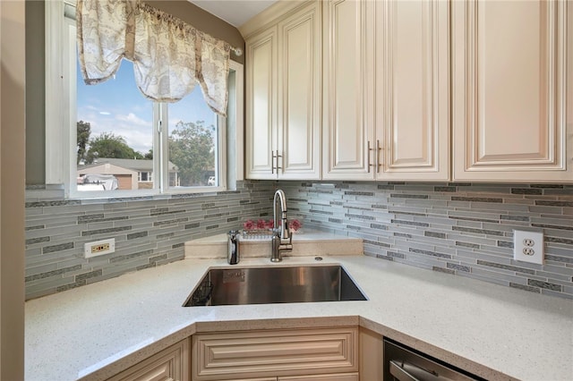 kitchen featuring light stone countertops, tasteful backsplash, stainless steel dishwasher, and a sink