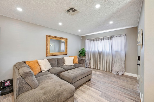 living room featuring visible vents, a textured ceiling, light wood finished floors, and recessed lighting