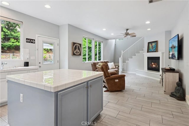 kitchen with tile counters, gray cabinets, recessed lighting, and open floor plan