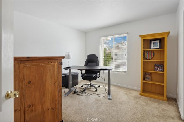office area featuring baseboards and light carpet