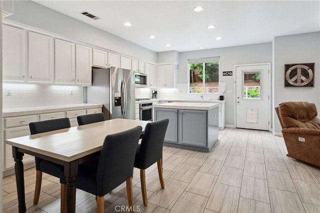 kitchen featuring gray cabinets, visible vents, appliances with stainless steel finishes, a center island, and recessed lighting