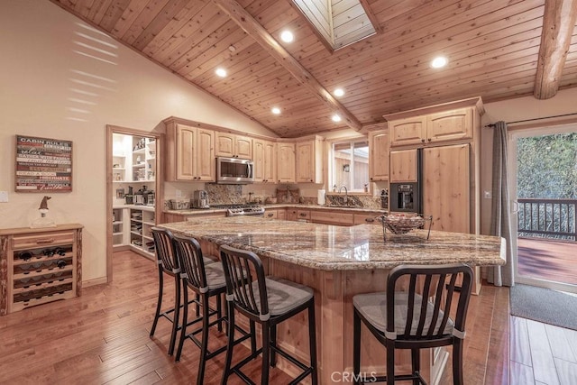 kitchen featuring light brown cabinets, paneled refrigerator, stainless steel microwave, range, and a sink