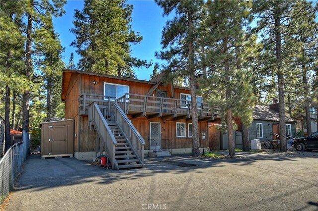 view of front of property with a wooden deck, a storage unit, stairway, and an outdoor structure