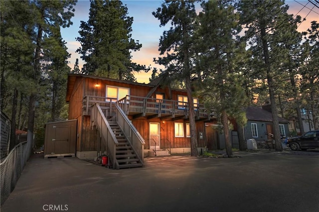 view of front of property with stairway, a storage unit, a wooden deck, and an outdoor structure