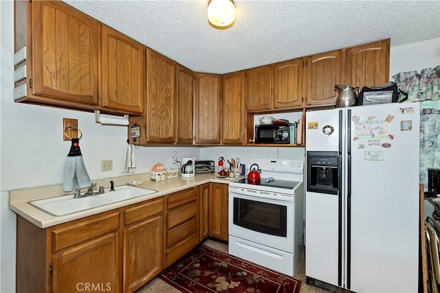 kitchen with a sink, white appliances, brown cabinetry, light countertops, and a textured ceiling