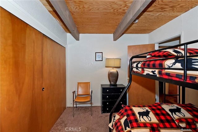 bedroom with beam ceiling, carpet floors, a closet, and wood ceiling