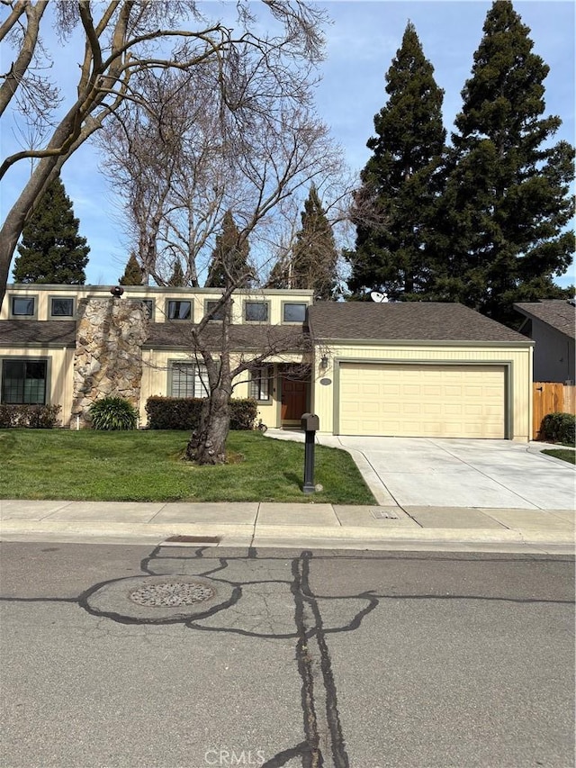 view of front of house featuring concrete driveway, a front lawn, and an attached garage